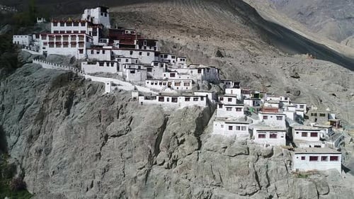 side view of an ancient buddhist monastery with a drone. extreme high altitude rocky himalayan mount