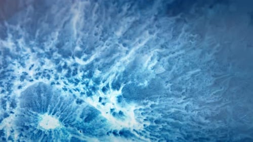 Vibrant blue and white ink swirling in water creating mesmerizing abstract patterns