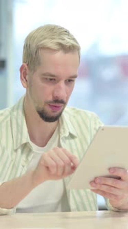 Enthusiastic Young Man Using Tablet Indoors