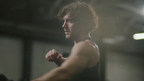 Strong Man Performing Seated One-Arm Rows on Rowing Machine at Gym