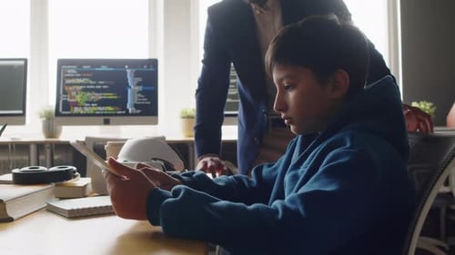 Profesor comprueba cómo un niño indio trabaja en una tableta en la clase de programación