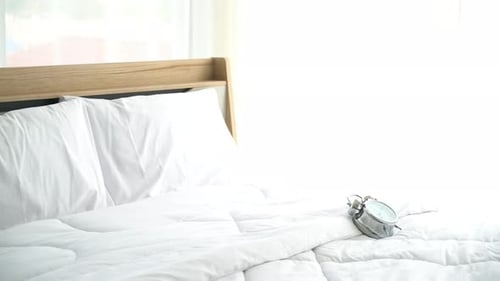 Silver Alarm Clock on a Bed in Bright Bedroom