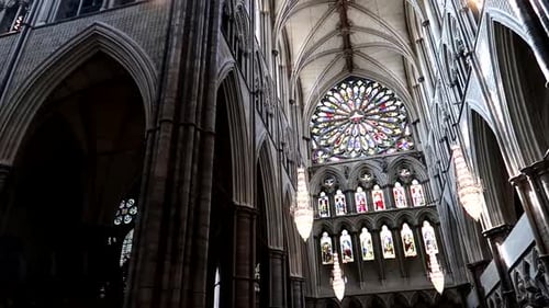 Inside of Westminster Abbey with a big stained glass rosette on top. Gothic cathedral decoration