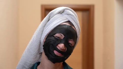 Woman Applies Black Facial Mask Close Up