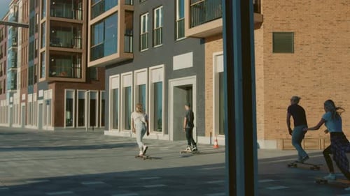 Group of Girls and Boys on Skateboards Through Fashionable Hipster District. Beautiful Young People