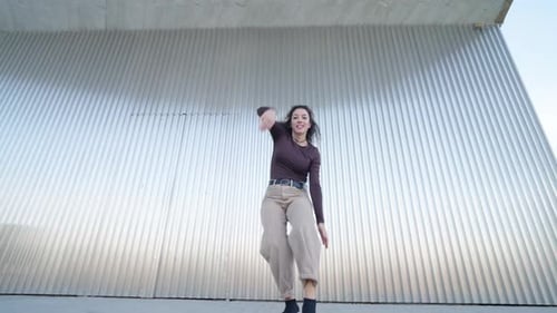 Young Woman Dancing Vigorously in Urban Setting