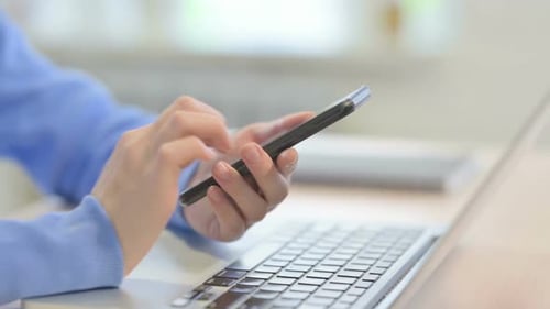 Close up of Woman Using Smartphone Near Laptop