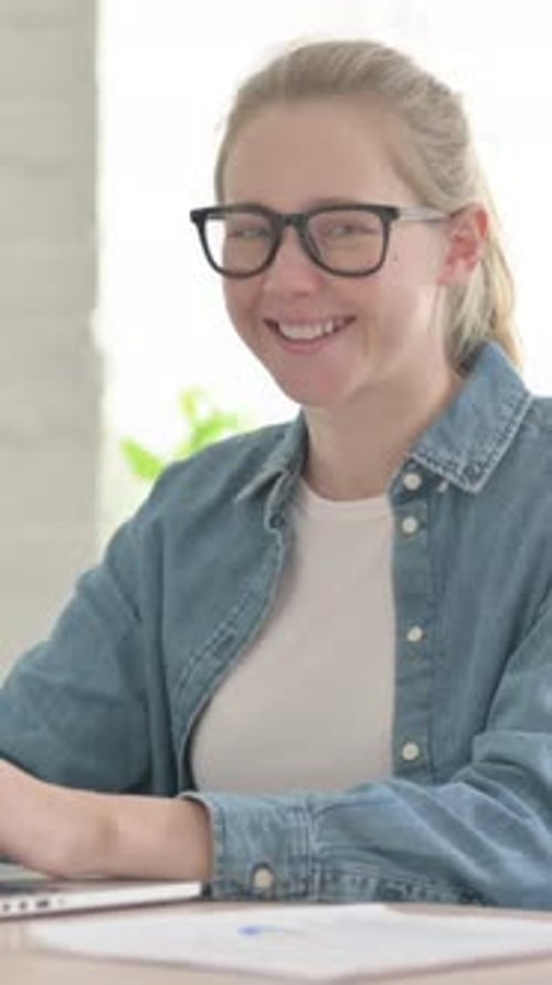 Beautiful Young Woman Smiling at Camera while using Laptop in Office, Vertical Video