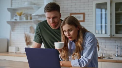 Couple Looking at Laptop in Modern Kitchen