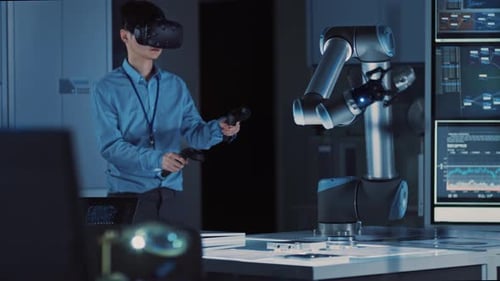 Un ingénieur de développement japonais professionnel en chemise bleue contrôle un bras robotique futuriste avec