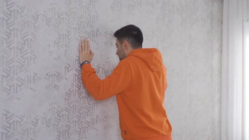 Man Leans Against Wall and Looks Around