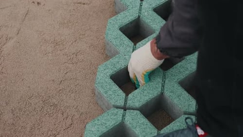 Worker Installing Permeable Grass Pavers on Prepared Ground