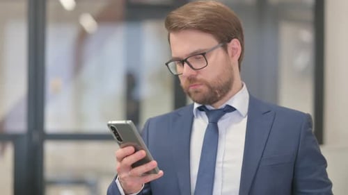 Man in Suit Using Smartphone in Office Setting