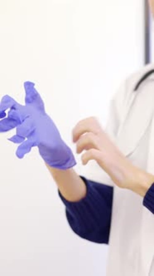 Unrecognizable Female Doctor Putting on Latex Gloves in a Clinic