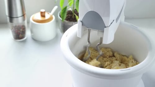 Mixer stirs the dough in a spinning bowl. A stationary mixer with a bowl kneads the dough