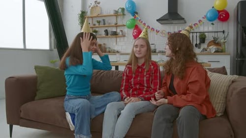 Carefree Adorable Adolescents Girls in Birthday Caps Having Fun on Sofa at Party