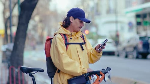 Delivery Man with Bike Using on Mobile Phone on Street
