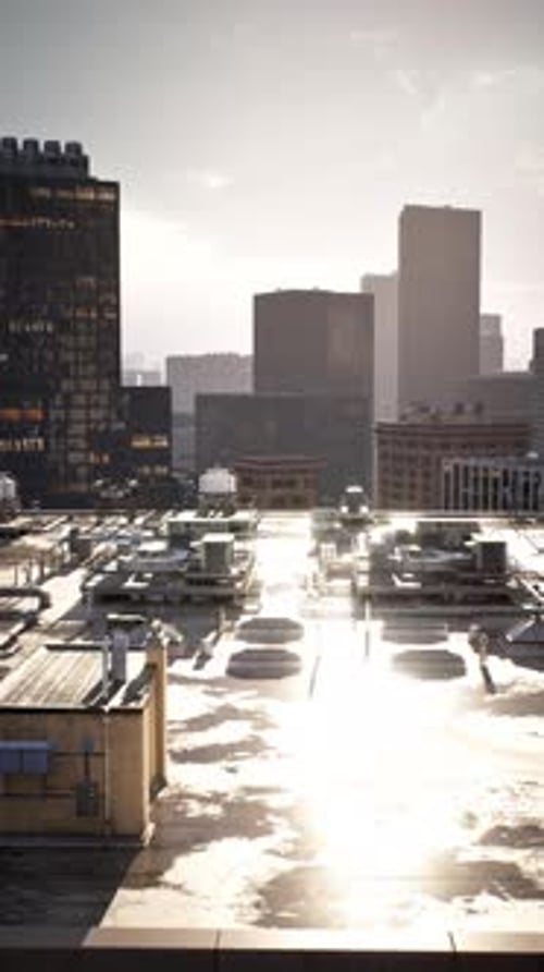 City Skyline View with Rooftops Reflecting Sunlight at Sunset
