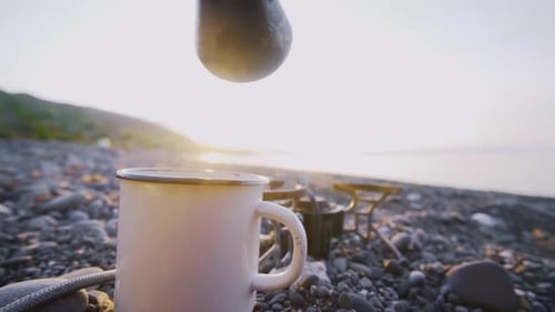 Woman Pours Coffee From Cezve Into Cup on Beach