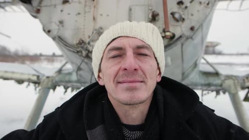 Man Standing Proudly Near Old Airplane in Winter
