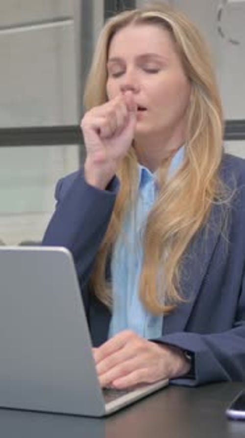 Woman Working at Laptop Coughing at Office Desk