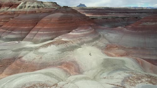 Vista aérea de una mujer corriendo cuesta arriba en un paisaje cerca de Hanksville, Utah, EE. UU.