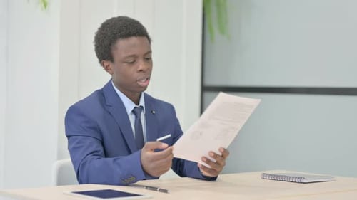 Young Adult Reviews Documents at Bright Office Desk