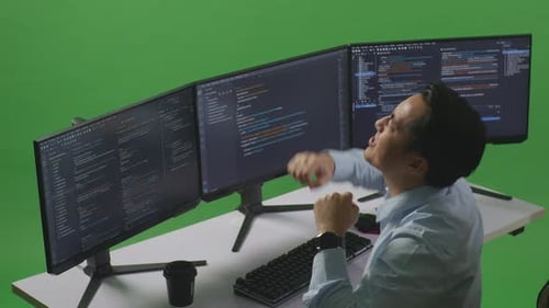 Happy Man Celebrating And Dancing While Write Code With Multiple Computer Screens In Green Screen