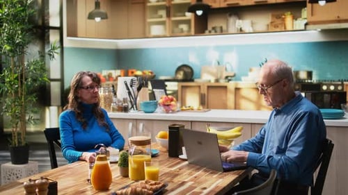 Man works on laptop next to woman drinks coffee