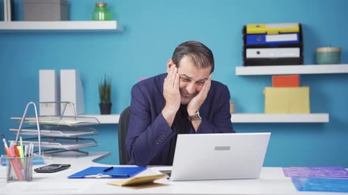 Stressed Man Works at Office Desk With Laptop