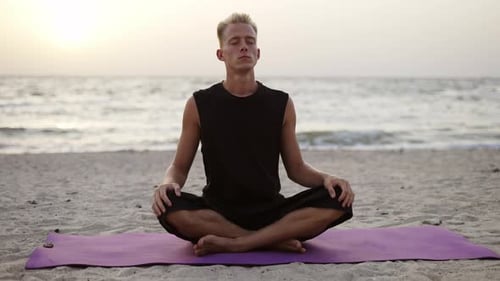 Man Meditates on Beach at Sunrise
