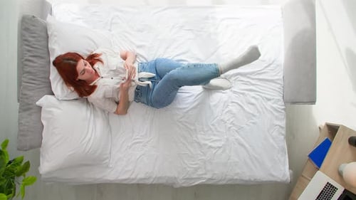 Woman Using Smartphone Lying on Bed at Home