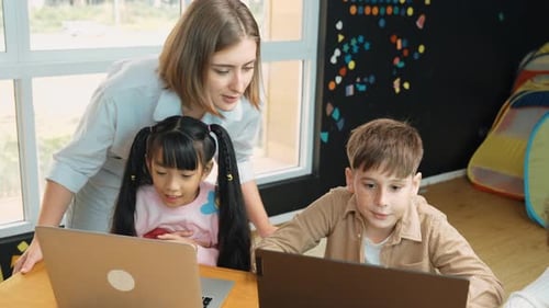 Caucasian teacher checking student answer while learner using laptop. Erudition.