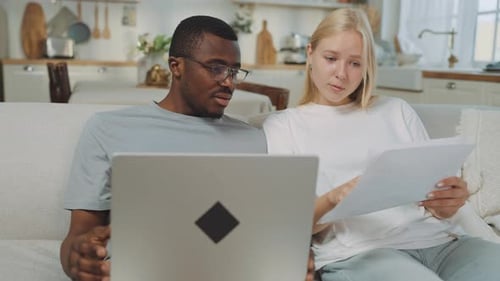 Man and woman discuss paperwork using laptop