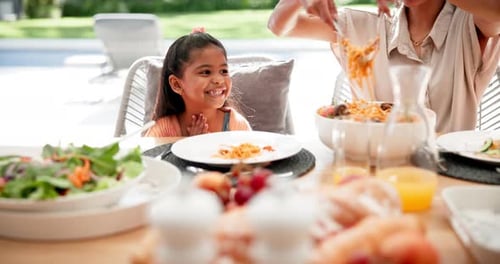 Child Eating Food with Adult at Outdoor Table