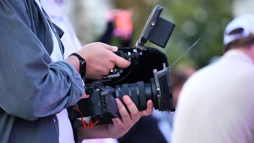 Camera Operator Filming with Professional Camera in Urban Setting