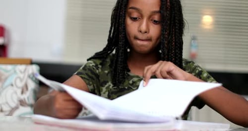 Focused Girl Studying and Writing in Notebook Indoors