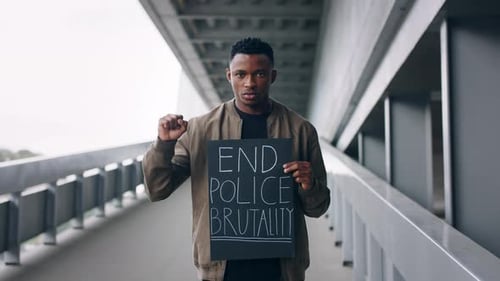 Man holding sign on a bridge raises fist