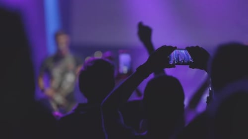 Silhouetted Crowd Enjoying Concert with Purple Lighting