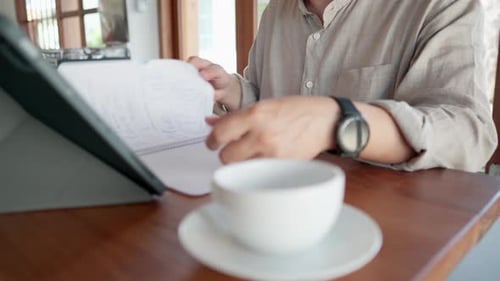 Close up of Asian man turns over the notebook pages in a cafe