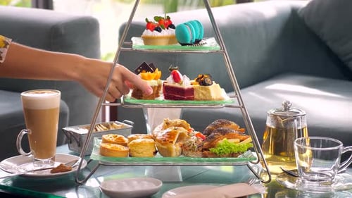 Woman Hand Take Slice of Cake From a Towering Display of Afternoon Tea