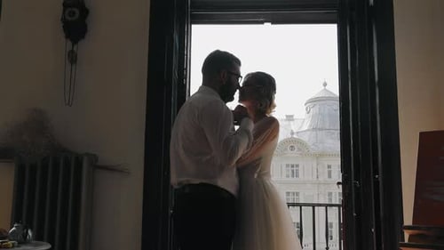 Couple Kissing in Wedding Attire on Balcony