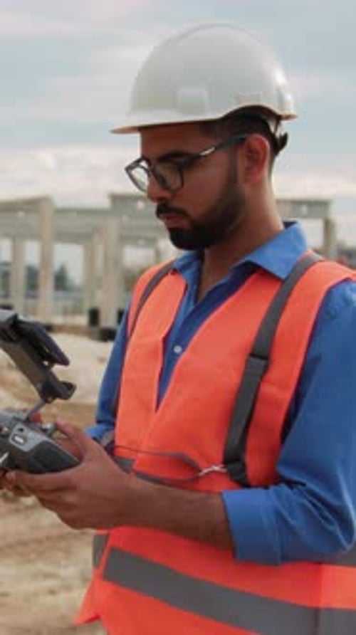 Portrait of Young Bearded Man in Glasses Operating Drone with Remote Control Footage of Male Builder