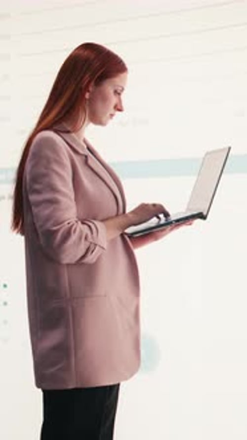 Vertical Video Comparing Profit Data Laptop and Businesswoman Using Charts