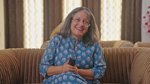 Old Indian woman watching funny show on TV
