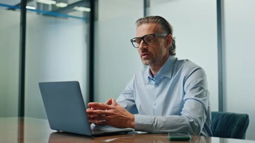 Man Talking On Laptop Video Call In Office