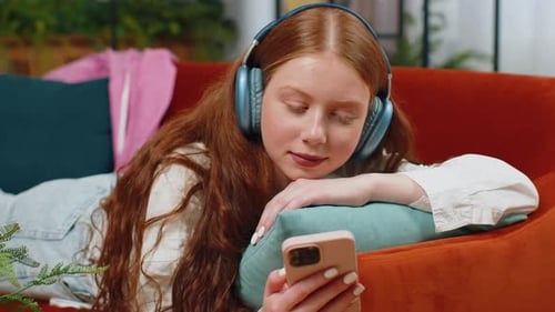 Woman Relaxes on Couch with Phone and Headphones
