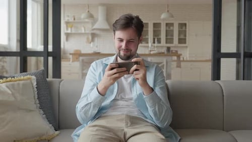 Young Adult Gaming on Phone at Home