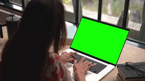 Woman Working on Laptop Computer with Green Screen and Typing on Keyboard Keys