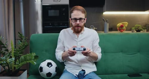 Young Man Plays Video Game at Home on Couch